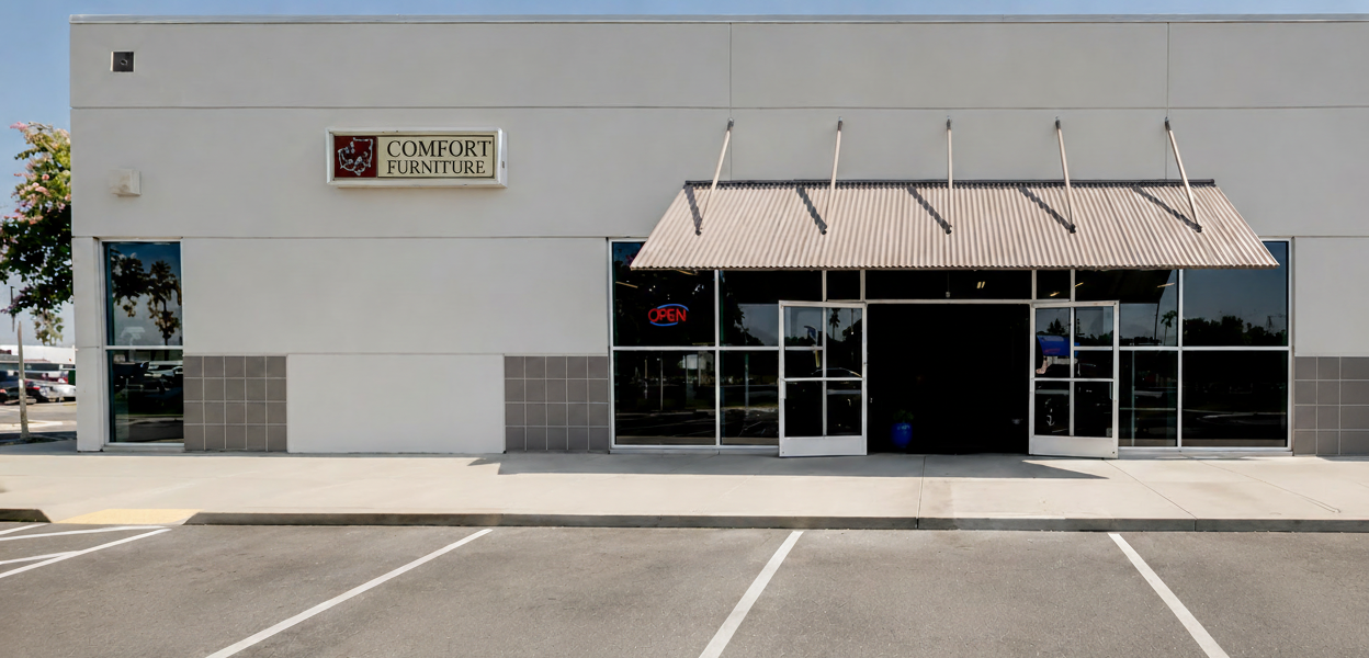 Commercial building with a sign that reads 'Comfort Furniture' on a clear day.